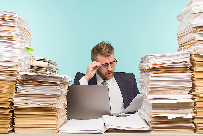 Business executive holds a video conference in the office and piles of paperwork, he is overloaded with work