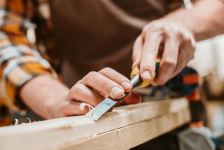 cropped view of carpenter carving wood on workshop
