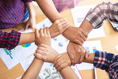 top view of employees standing around in a circle with their han