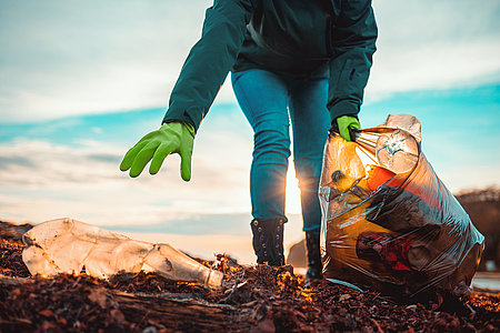 A volunteer collects garbage on a muddy beach. Close-up. The con