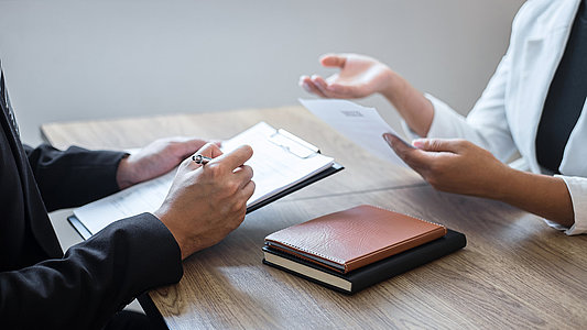 Employer or committee holding reading a resume with talking duri