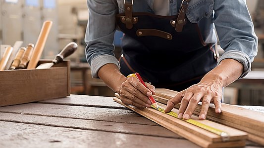 Carpenter working with equipment on wooden table in carpentry sh